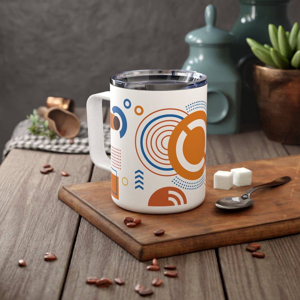 White mug with orange and blue geometric design on a wooden cutting board with coffee beans and sugar cubes.
